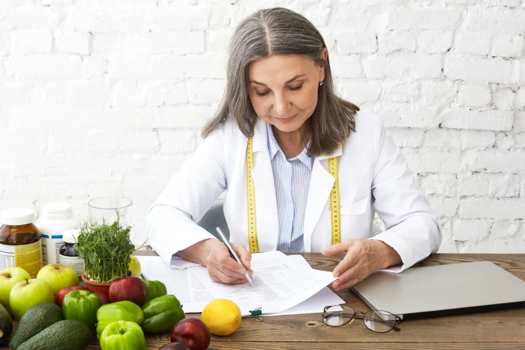 Nutricionista diseñando un plan alimenticio saludable, rodeada de frutas y verduras, para el control de peso tras la Manga gástrica en Riohacha.