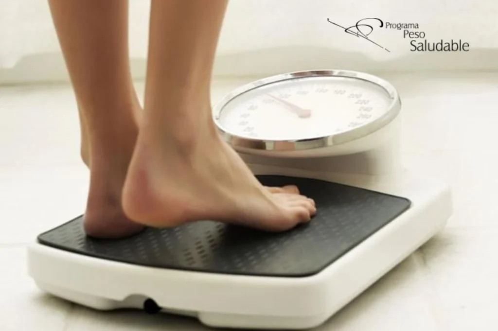 Persona descalza subiéndose a una báscula de control de peso, parte del Programa Peso Saludable.