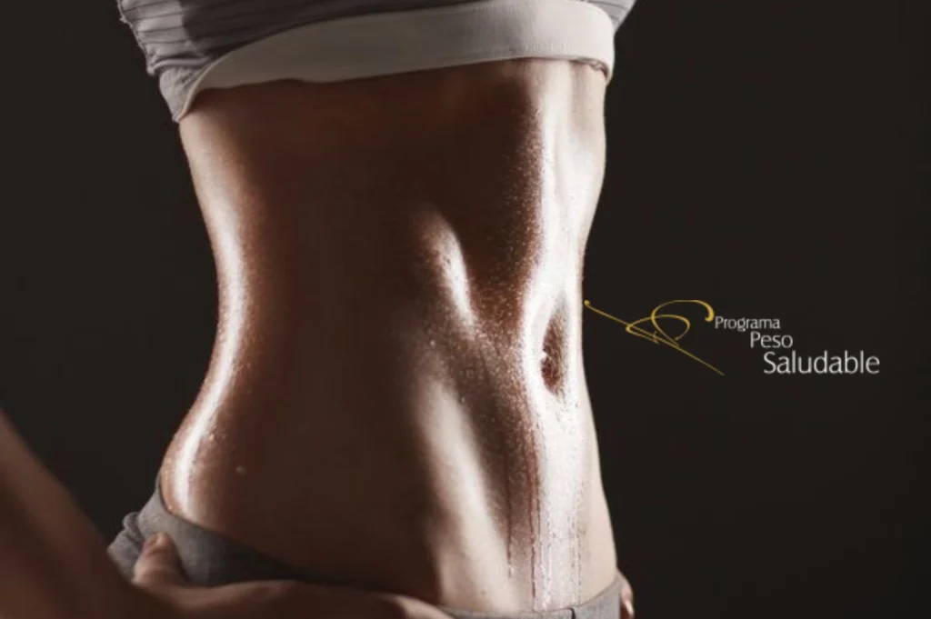 Abdomen tonificado y definido de una persona con piel brillante por el sudor, representando los resultados de un programa de control de peso saludable.
