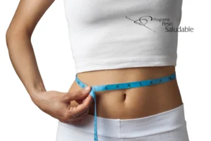 Persona midiendo su cintura con una cinta métrica azul, representando el control del peso y los resultados del Programa Peso Saludable