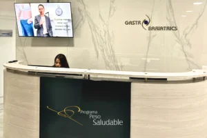 Recepción moderna de la Clínica de la Obesidad con branding de Programa Peso Saludable y personal administrativo atendiendo a los pacientes.