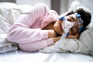 Mujer descansando con mascarilla de presión positiva continua (CPAP) para tratar la apnea del sueño, símbolo del bienestar y recuperación del Programa Peso Saludable.