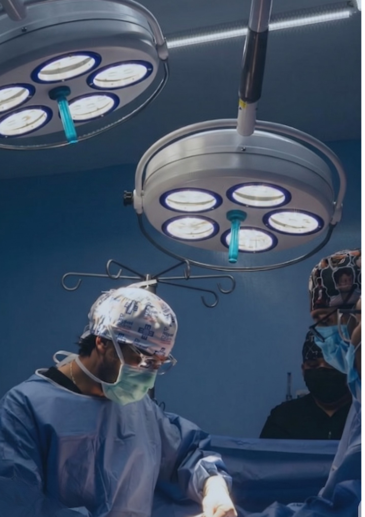 Cirujano realizando un procedimiento bariátrico en quirófano con equipo médico especializado y luces quirúrgicas.